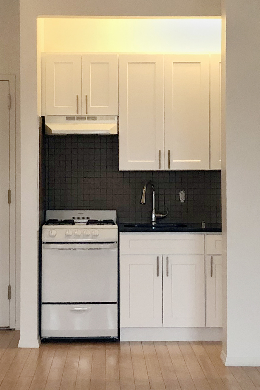 White kitchen cabinets with a black backsplash