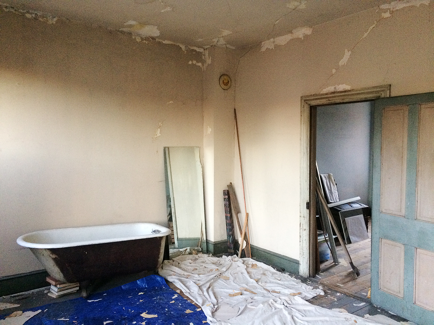 damaged room with tarps and a tub in the center