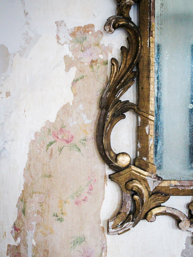 brass mirror with floral wallpaper peeking through