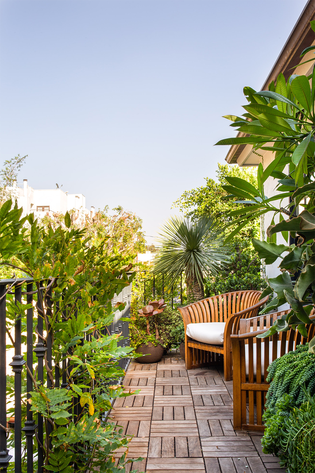 balcony with lots of plants and wooden armchair