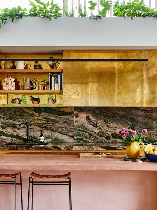 Kitchen with brass cabinets and pink island