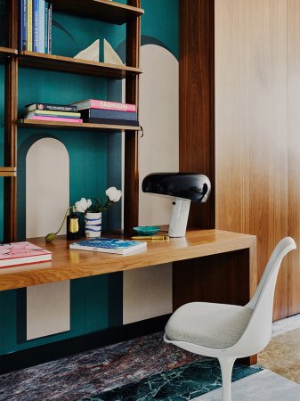 turquiose wall with white chair and wood desk