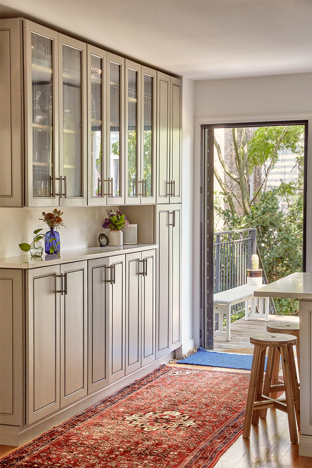 cream colored glass front kitchen cabinets and red rug