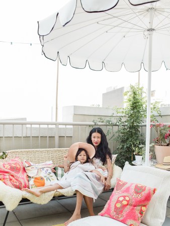 woman and child on outdoor sofa under umbrella