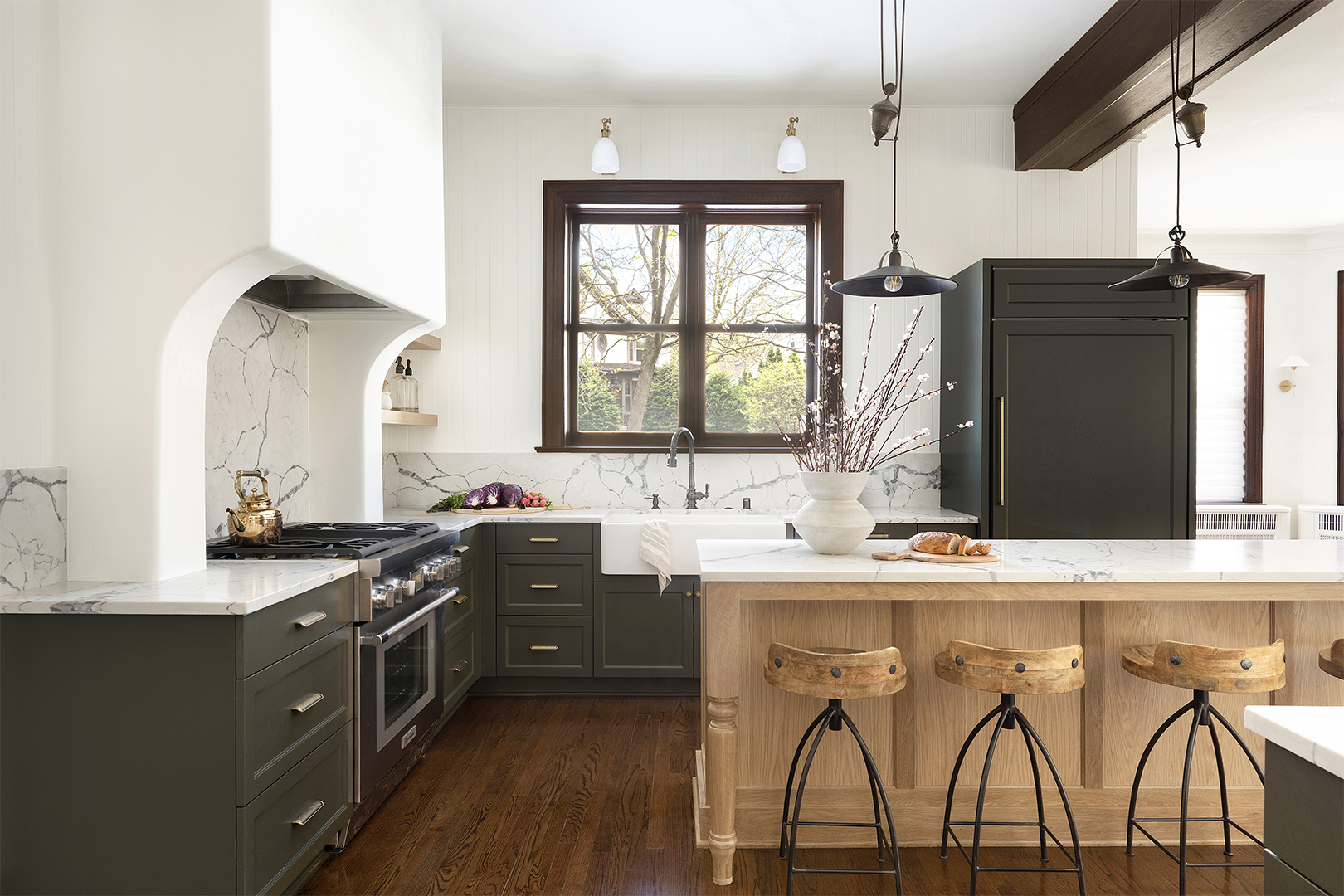 Traditional kitchen with green cabinets and dramatic range hood