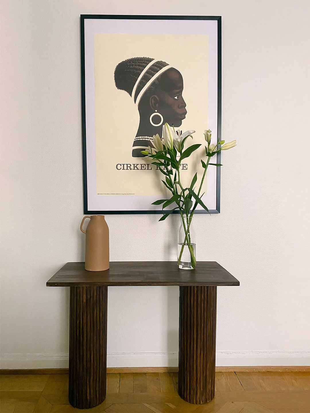 brown ribbed console table vignette with poster and vase