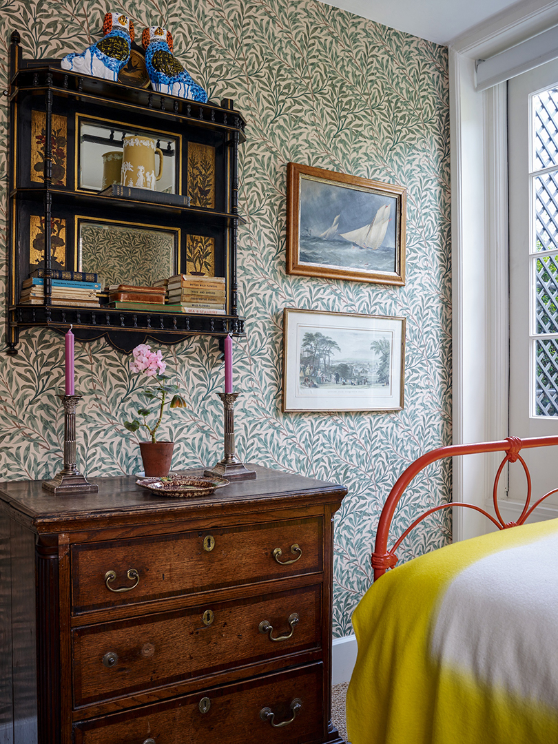 Bedroom with leafy wallpaper and red bed frame