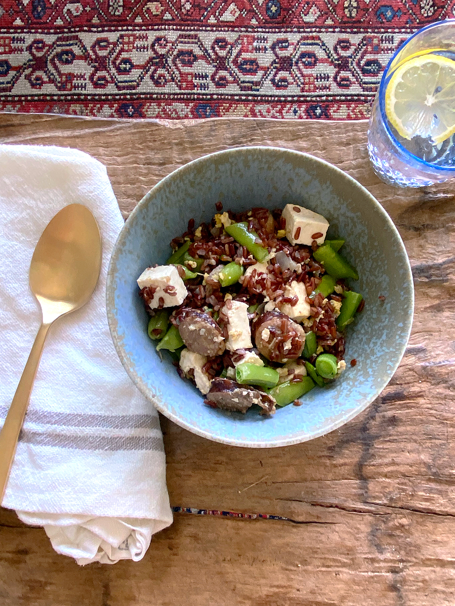 stir fry in a blue bowl with brass spoon