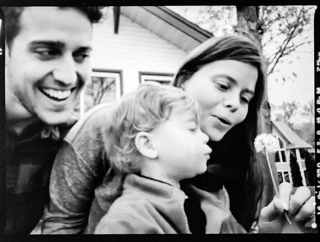 family blowing on flower