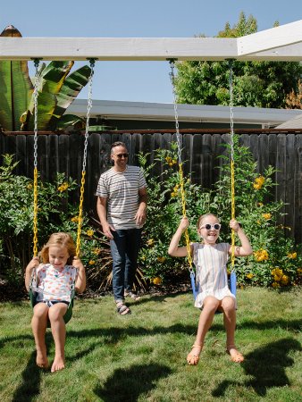 man pushing kids on swing