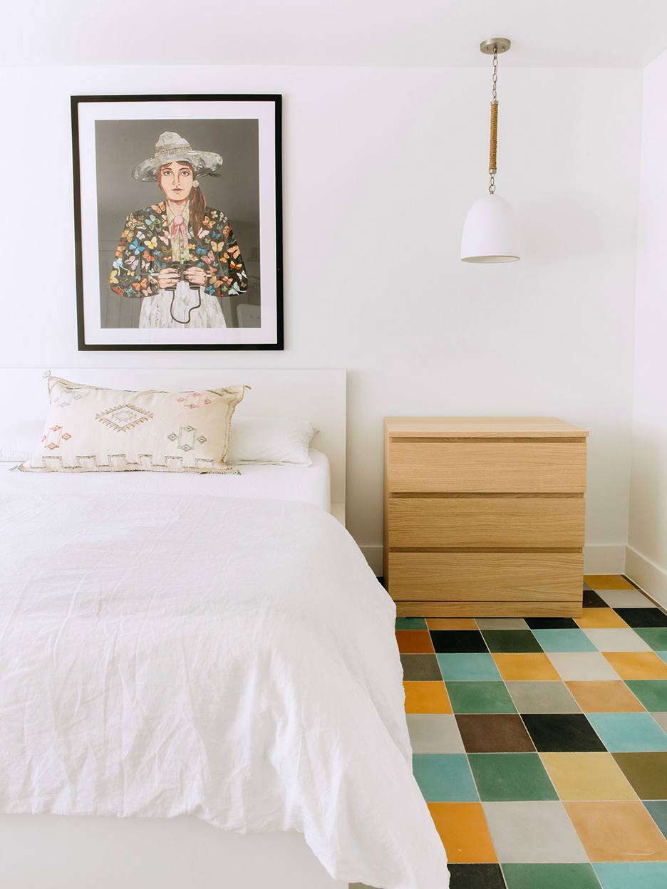 white bed with colorful floor tiles