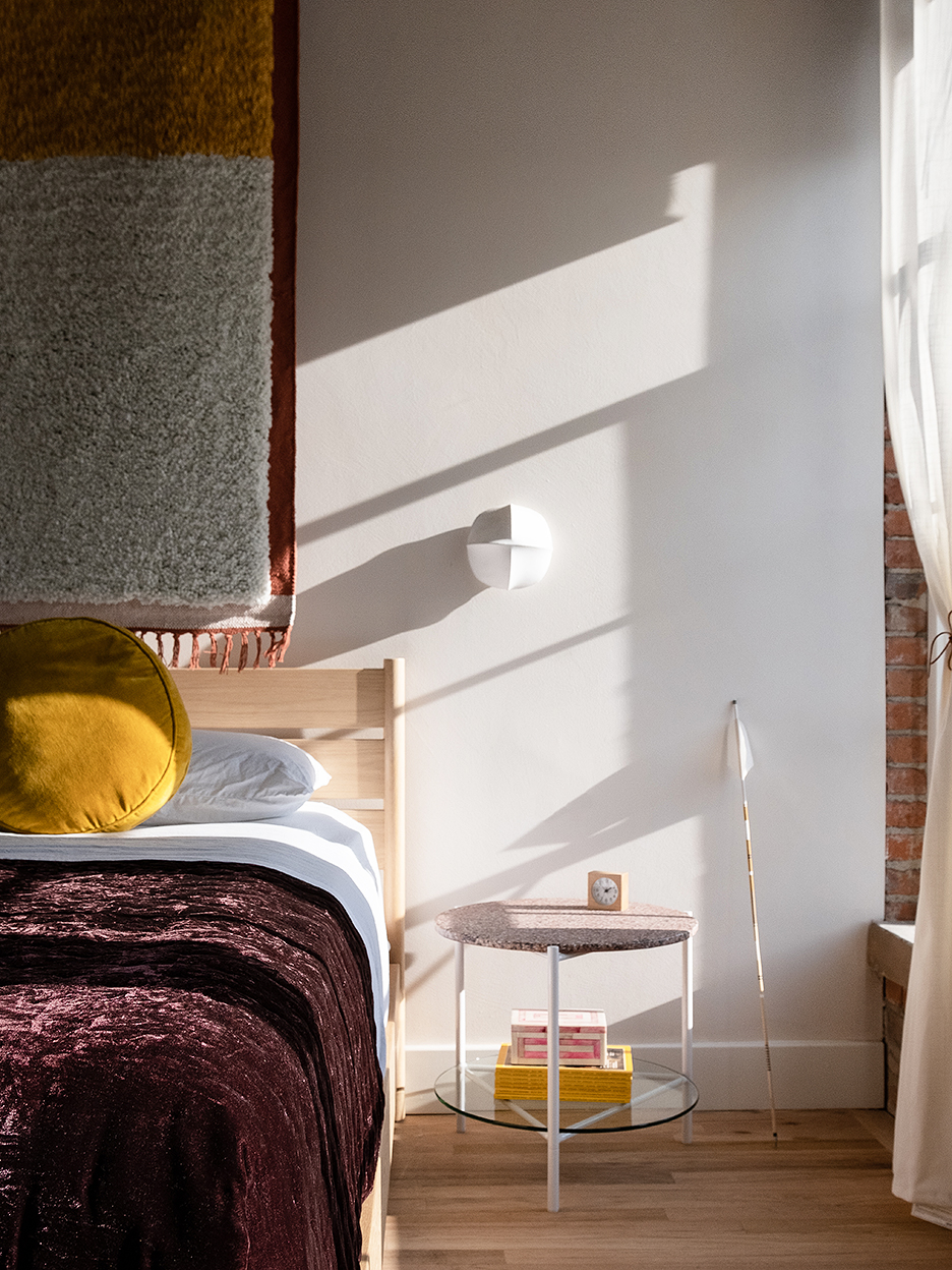 bedroom with purple bed spread and white sconce