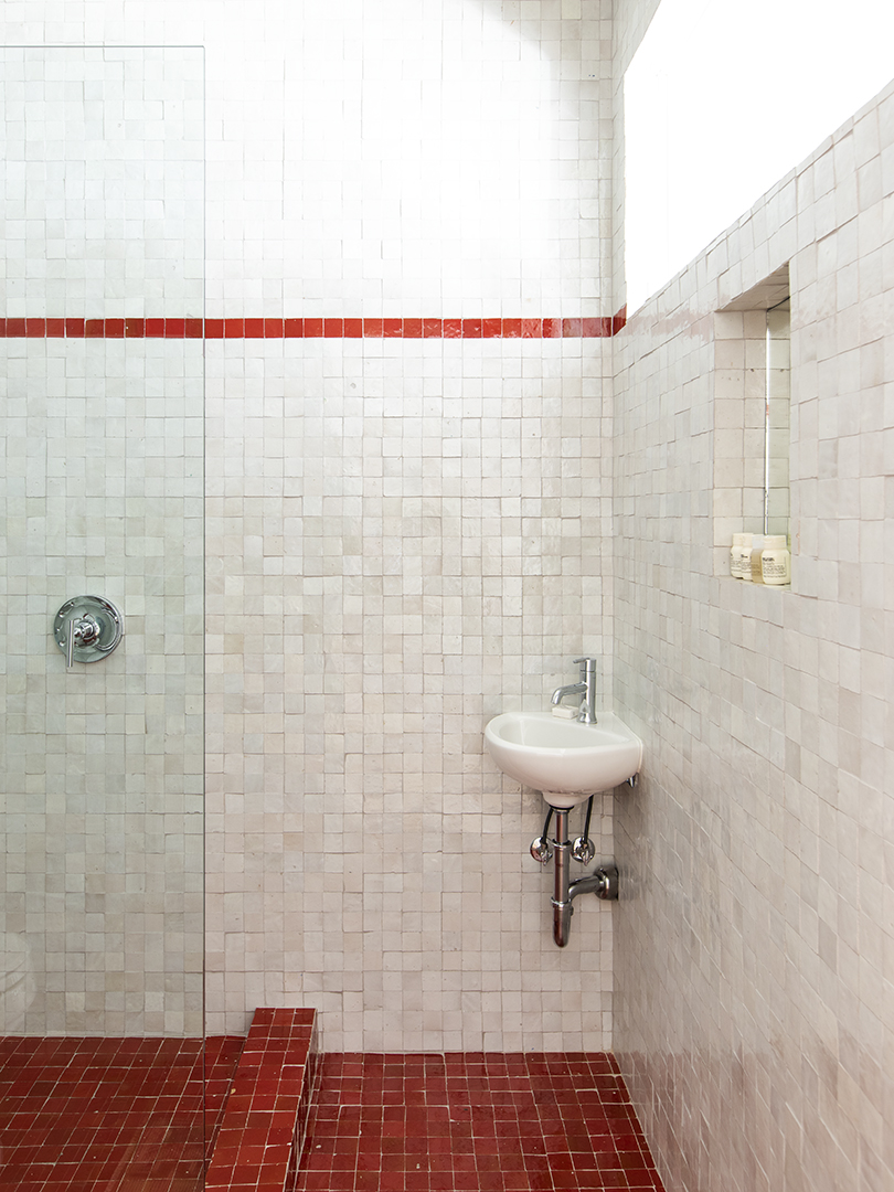 white zellige tile shower nook with strip of red tiles