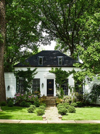 white cottage behind lots of trees