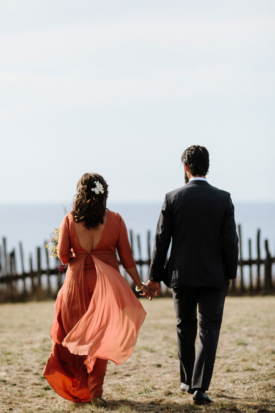 couple walking hand in hand towards fence