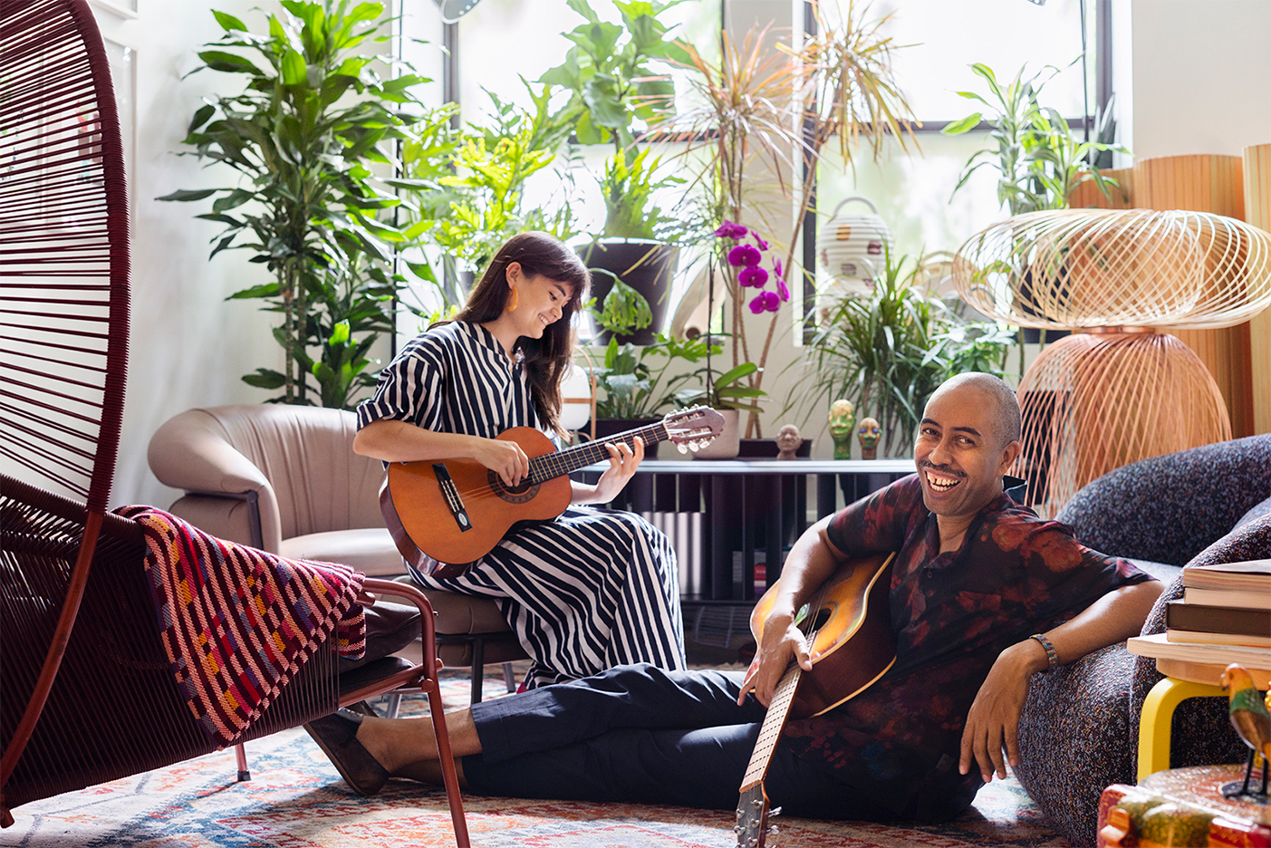 Stephen Burks and Milka Leiper playing guitar in living room