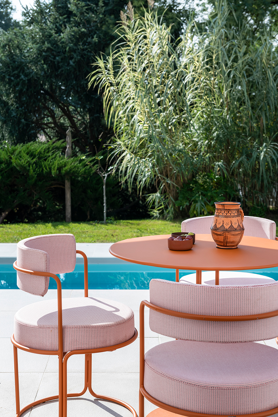 pink outdoor dining set in front of pool