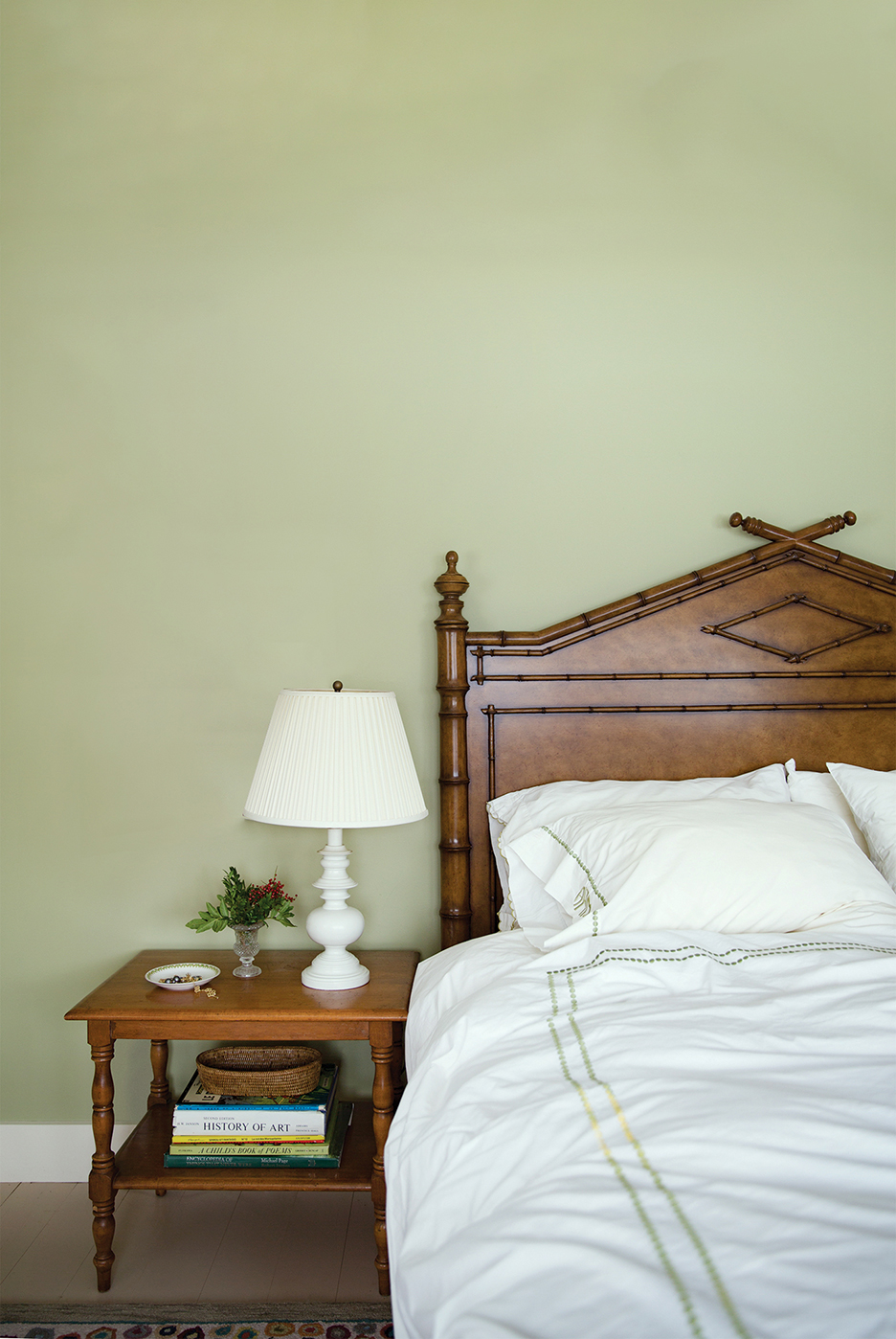 Sage green wall in front of bed