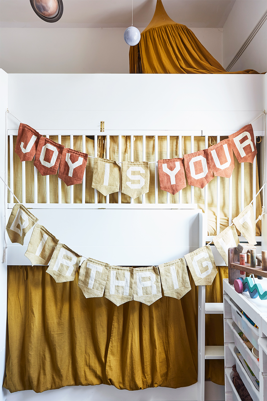 Banner reading "Joy Is Your Birthright" strung across kids' bunkbed.