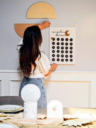 woman hanging art on wall