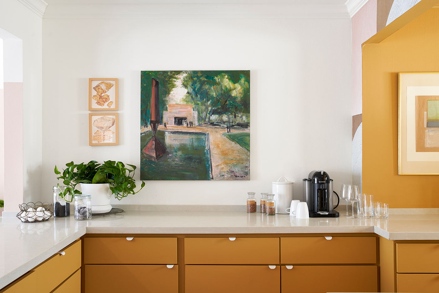 landscape painting above orange kitchen cabinets