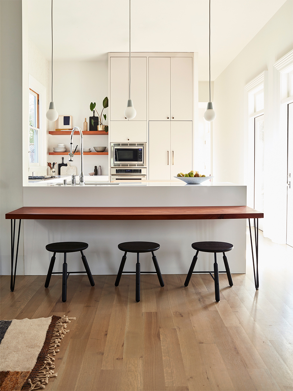 white kitchen with wood dining table and stools