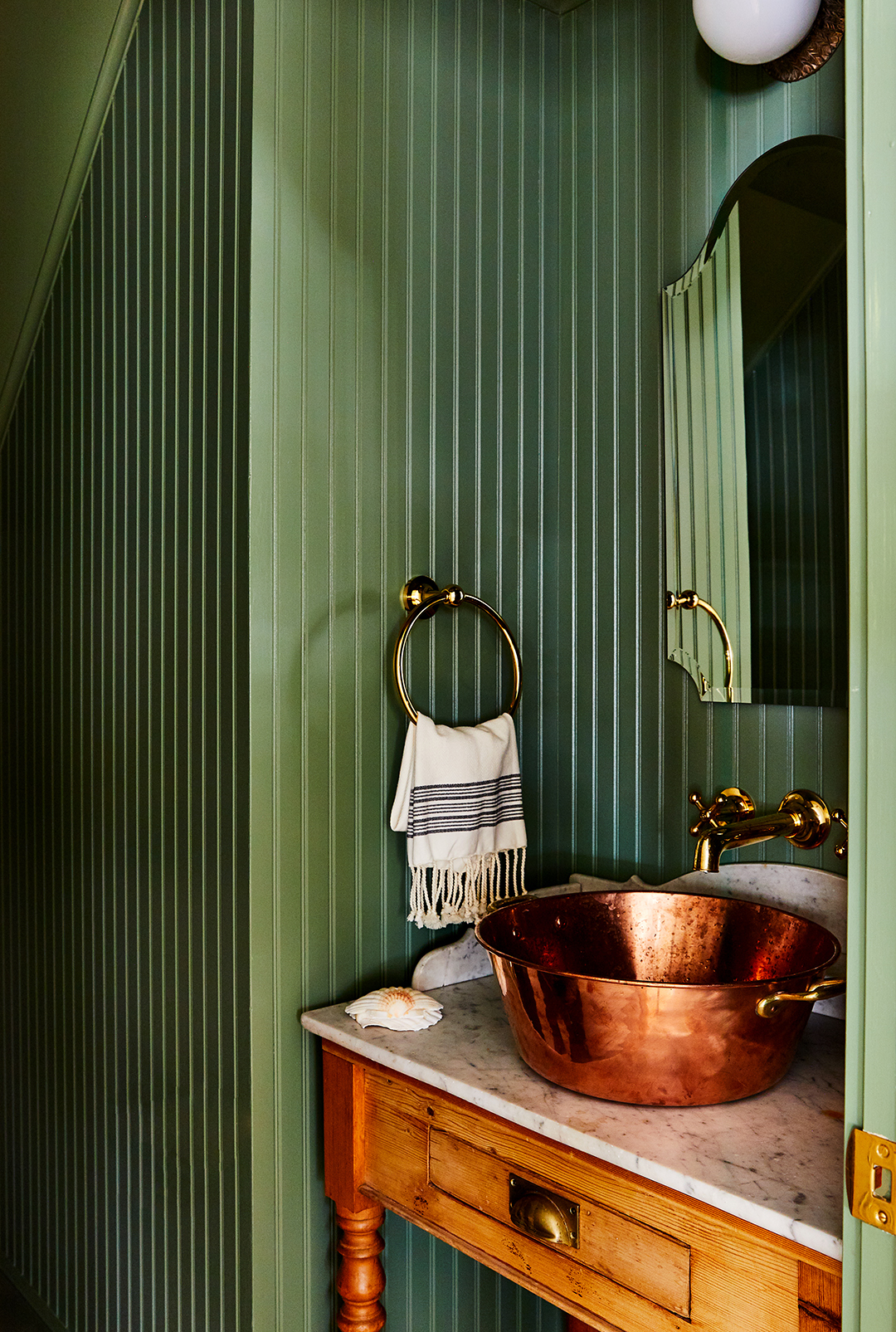 green paneled powder room with brass sink
