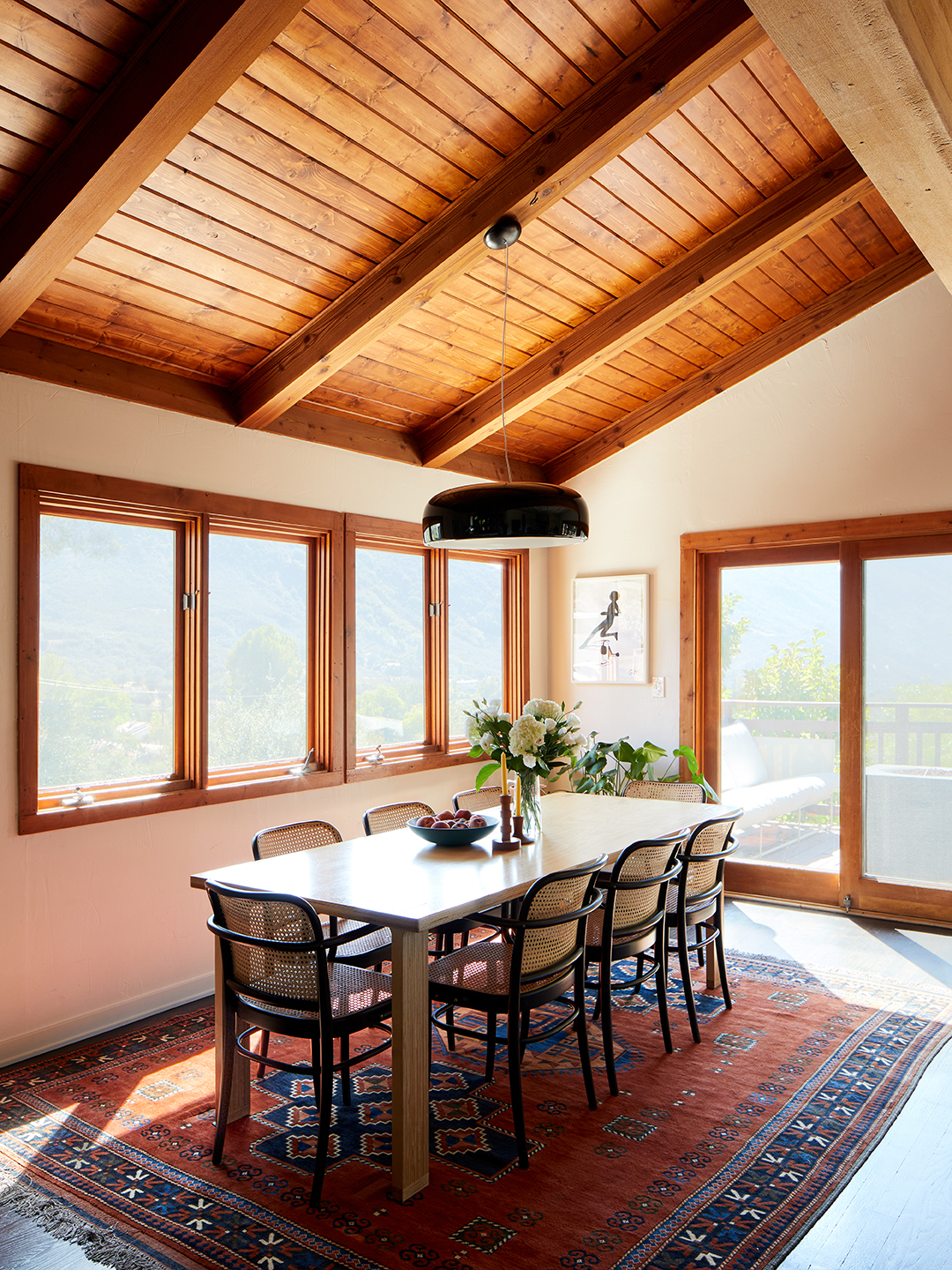 dining room with cane chairs and red rug.