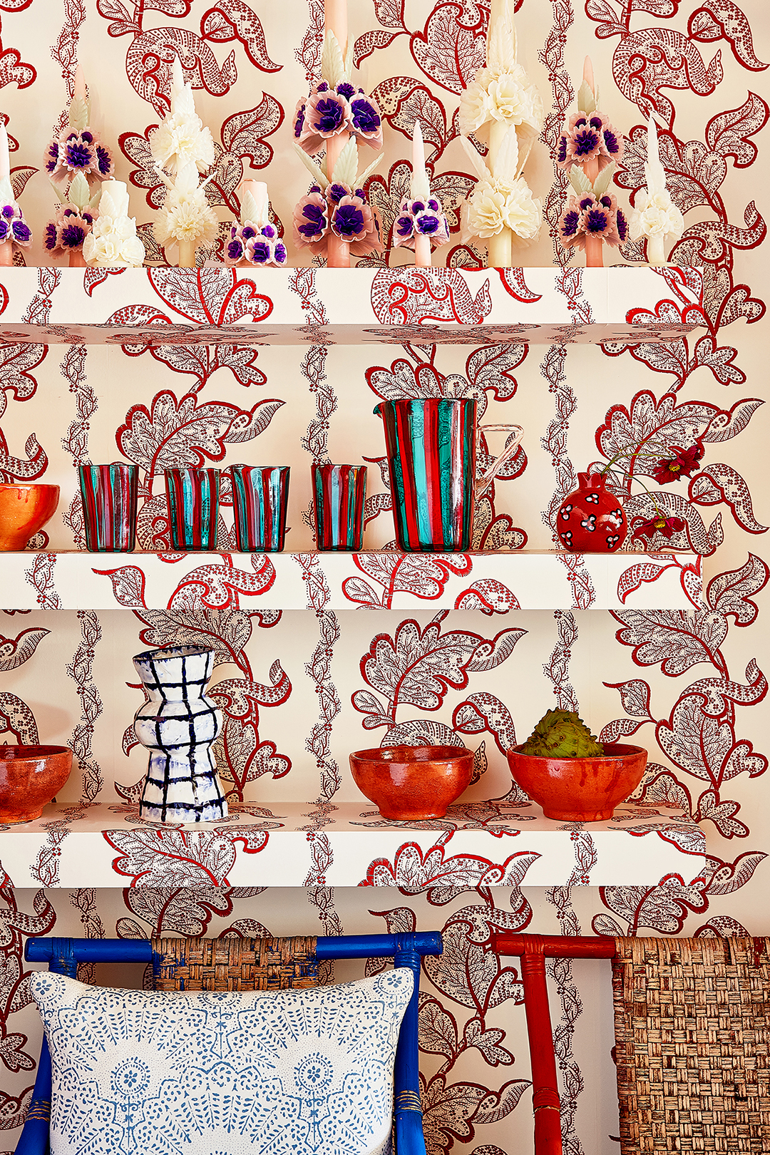 Glasses and vases on shelf covered with wallpaper