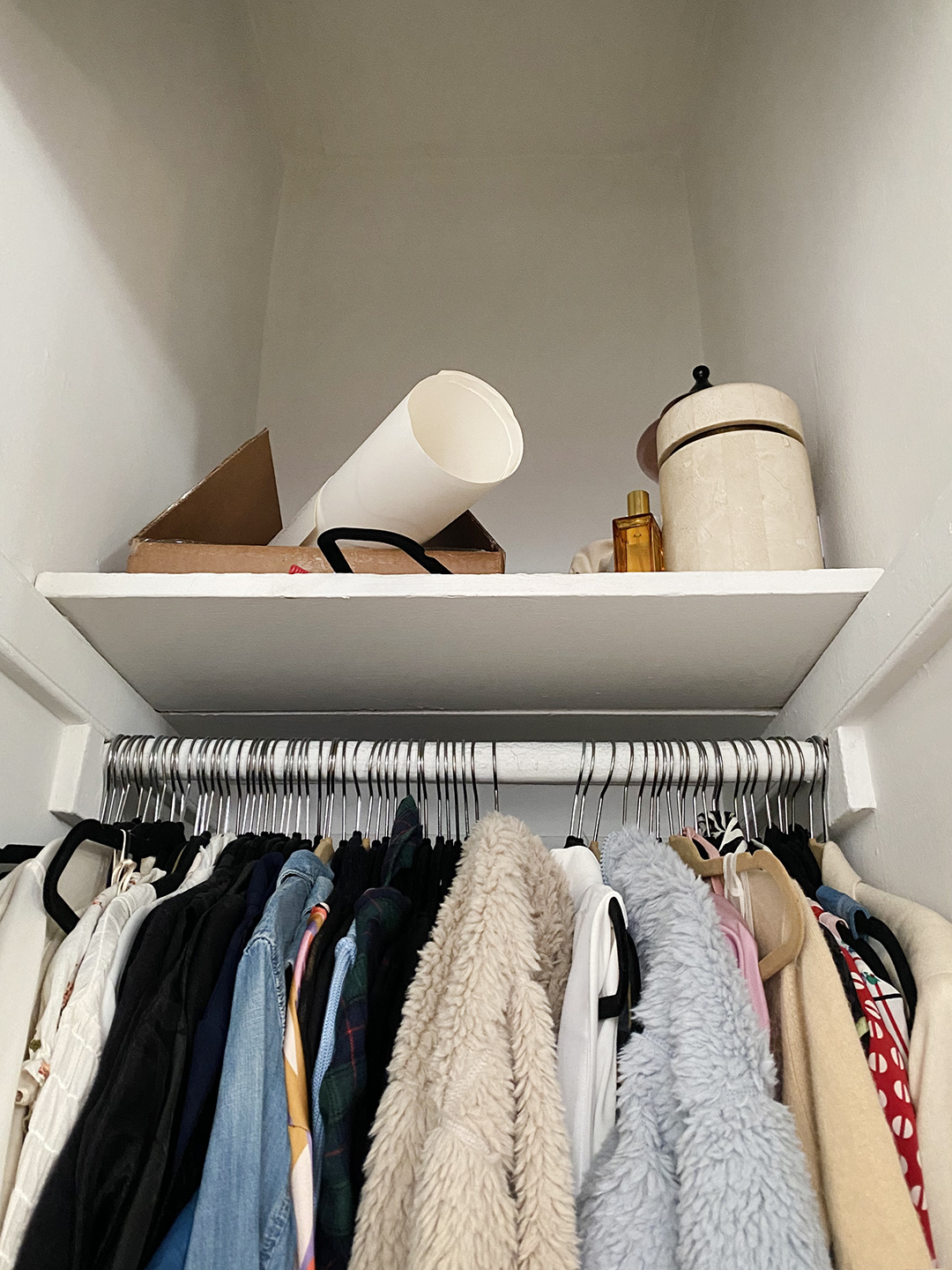 Top shelf of tiny closet with messy items on top