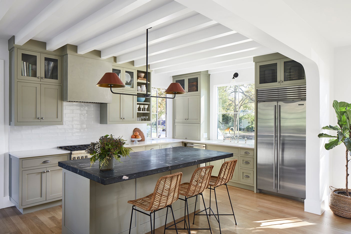 Green cabinets and kitchen island with wicker bar stools