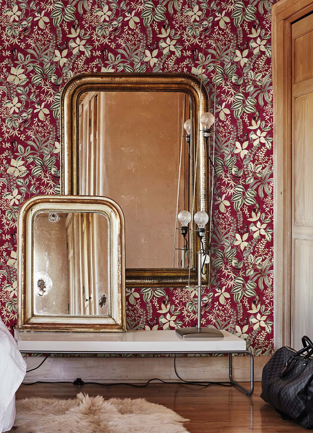 crimson flower wallpaper behind gold trim mirror