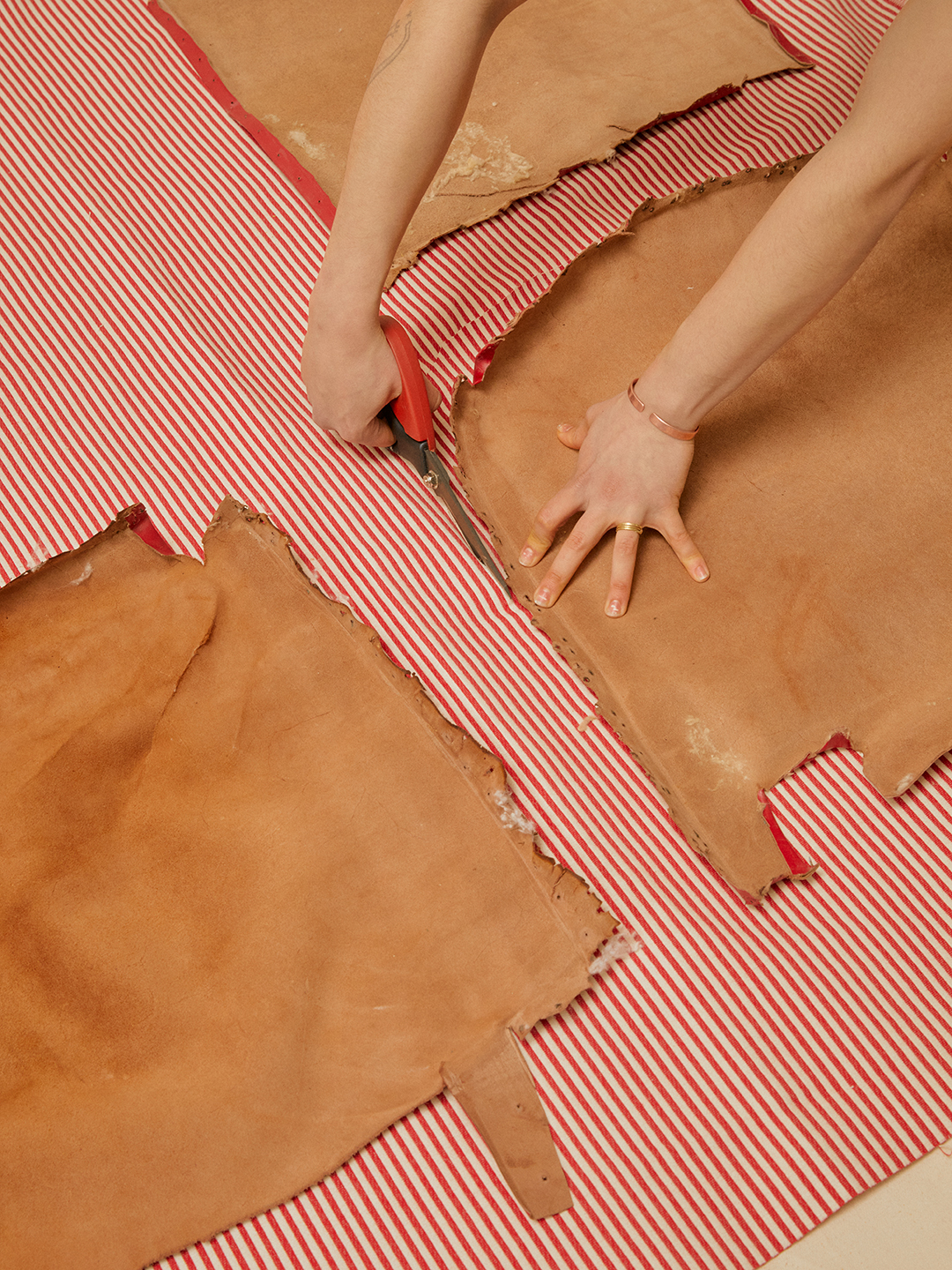 hand trimming red and white striped fabric with scissors