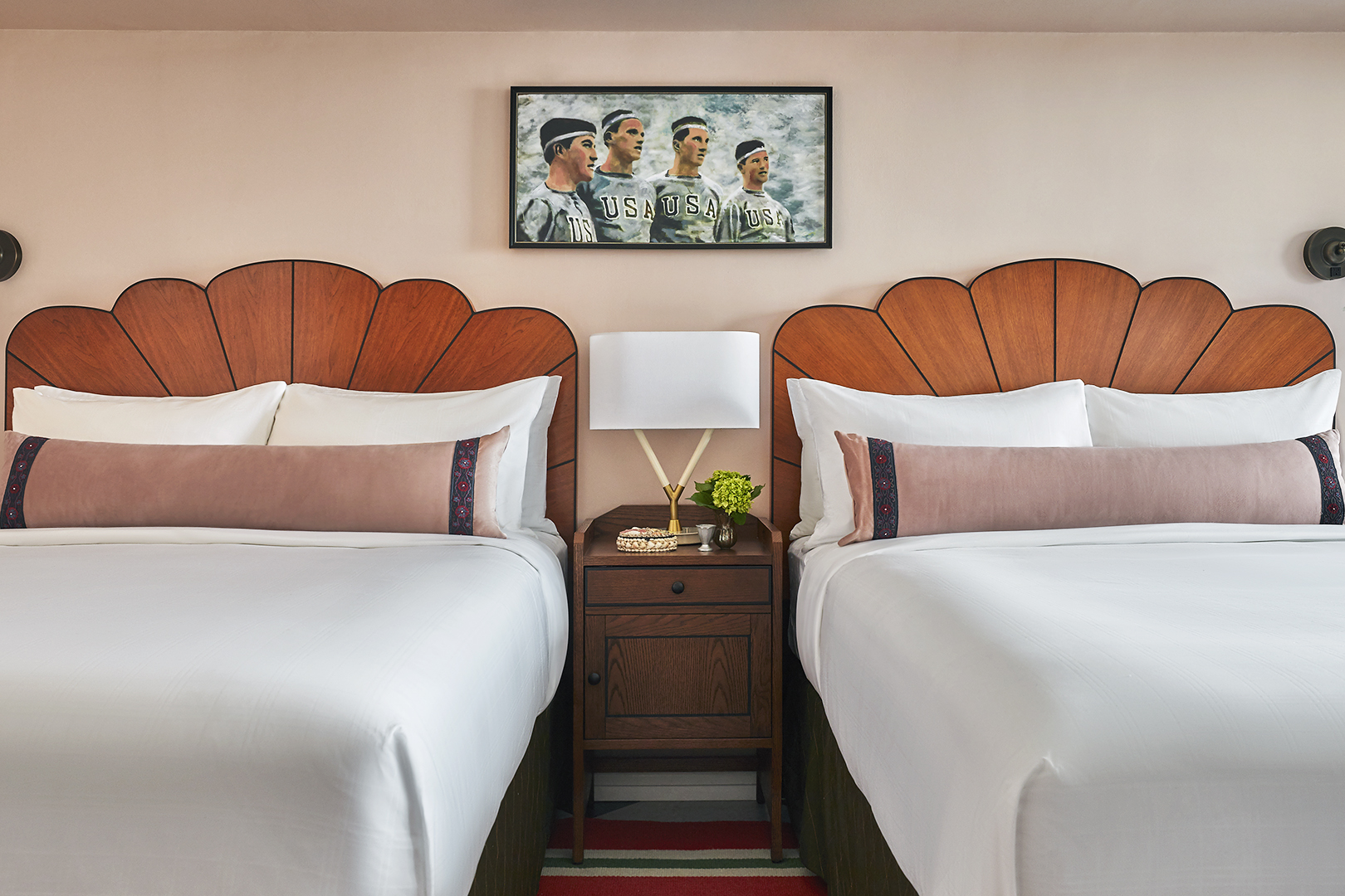 two queen beds with scalloped, arched wood headboards.