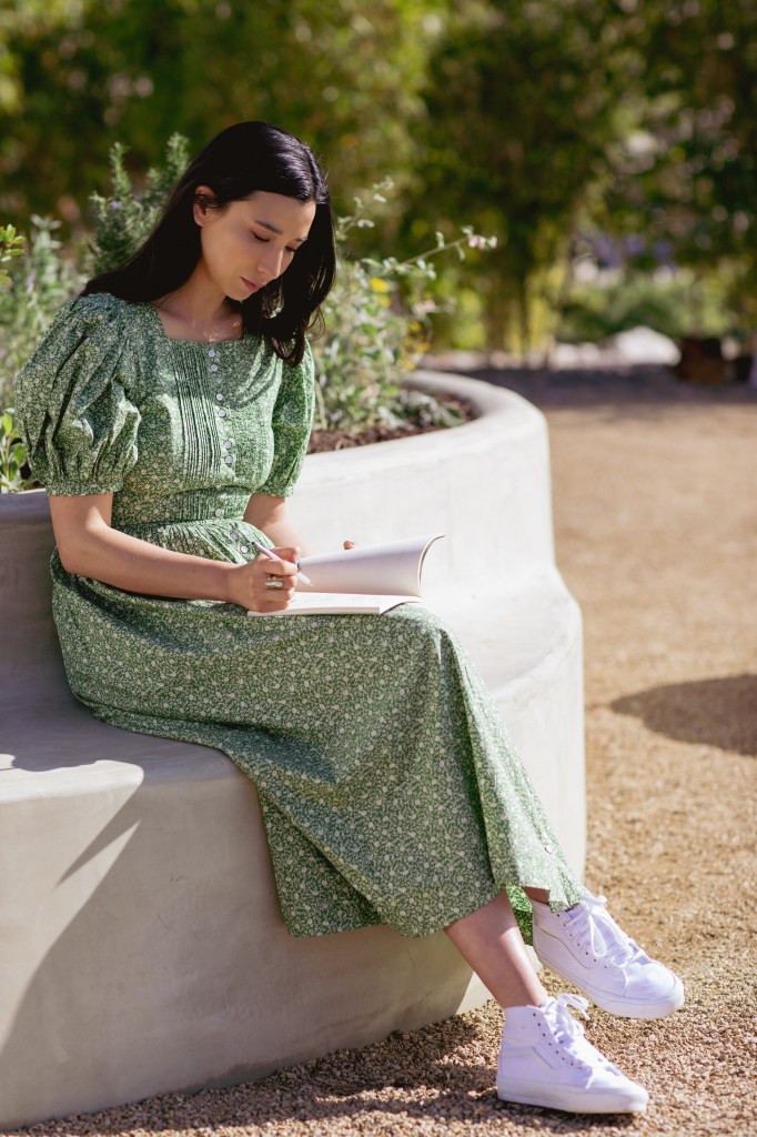 Lily Kwong writing in journal on bench built into planter