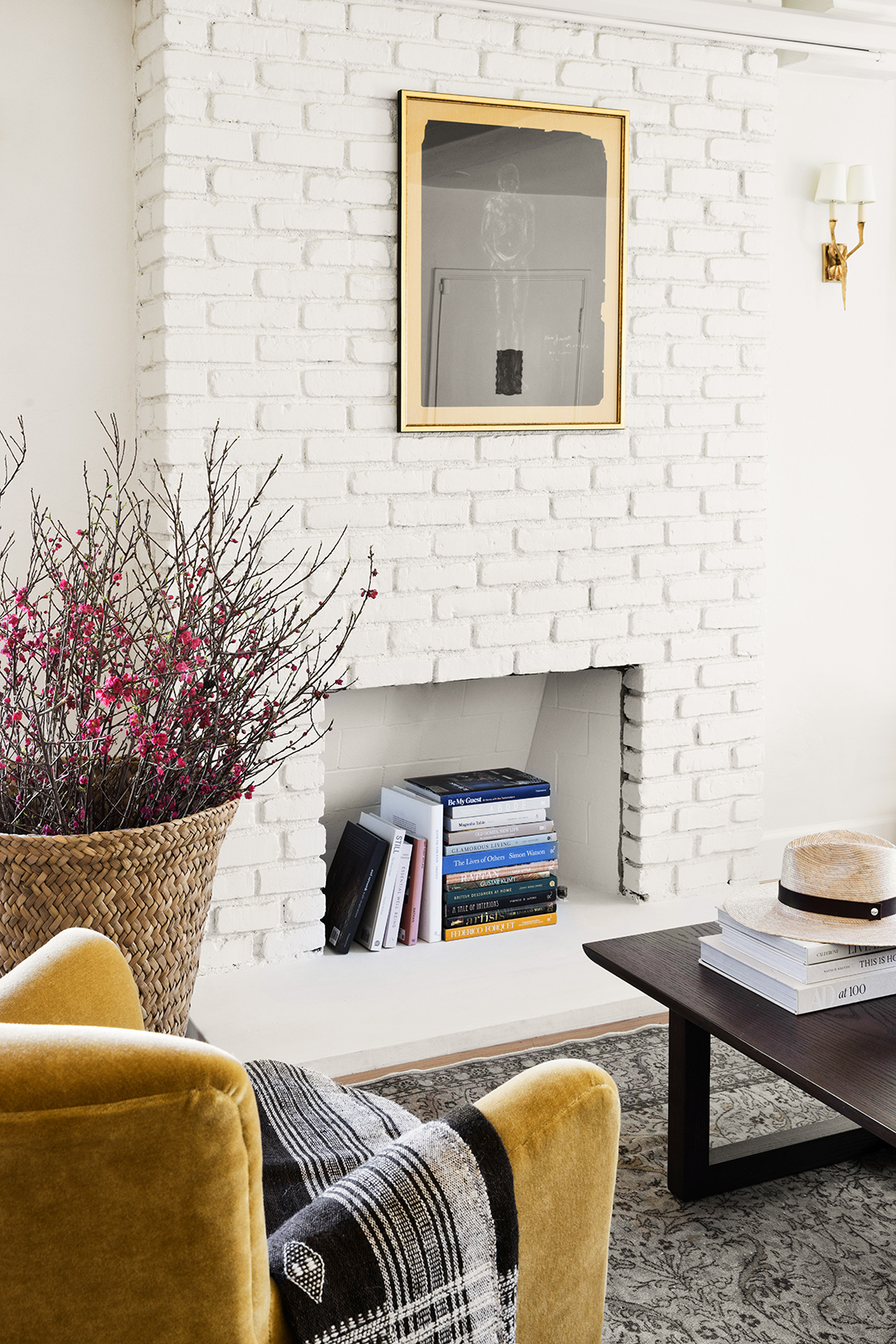 Yellow velvet chair placed near white exposed brick wall.