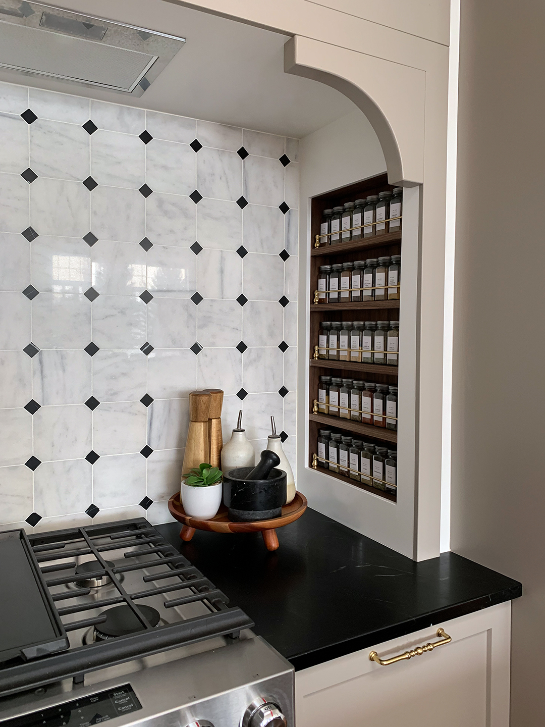 inset spice rack next to stove with marble backsplash