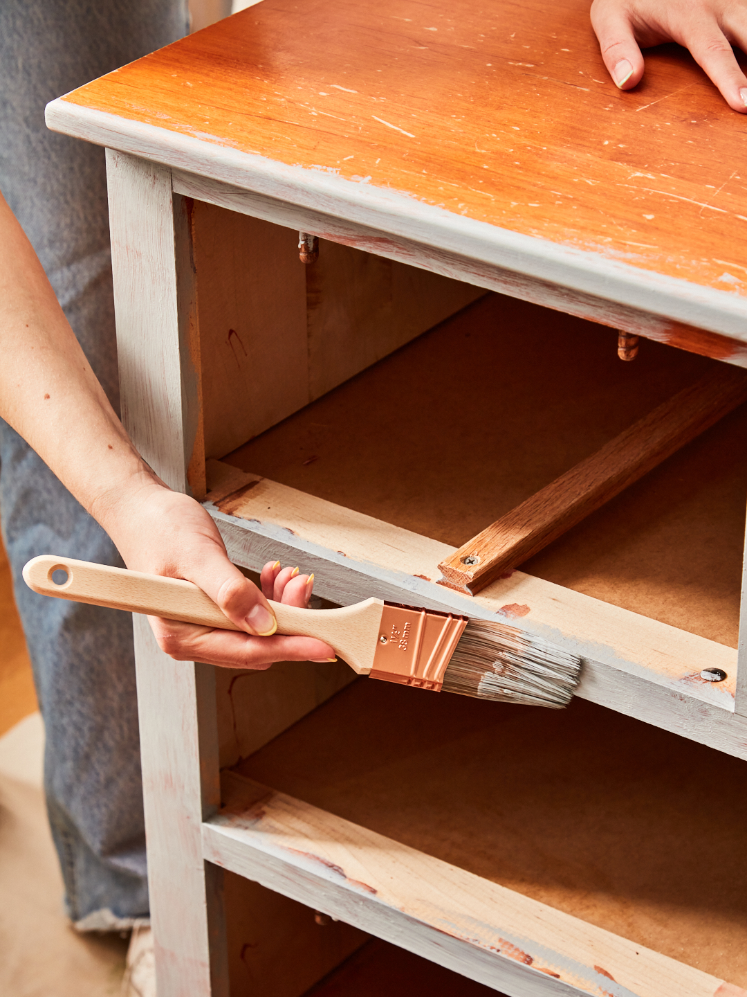 using a brush to apply primer to a wooden dresser frame