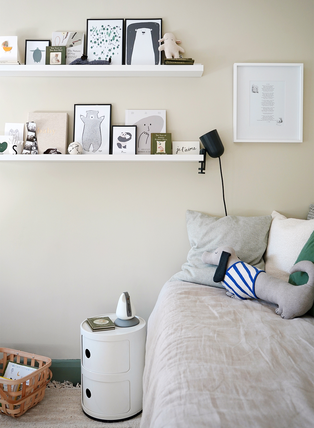 neutral day bed with floating shelves of artwork above