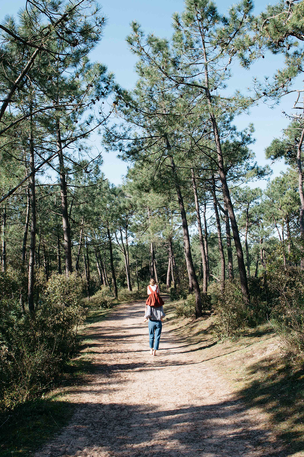 Outside shot of mother with child on shoulders surrounded by trees 