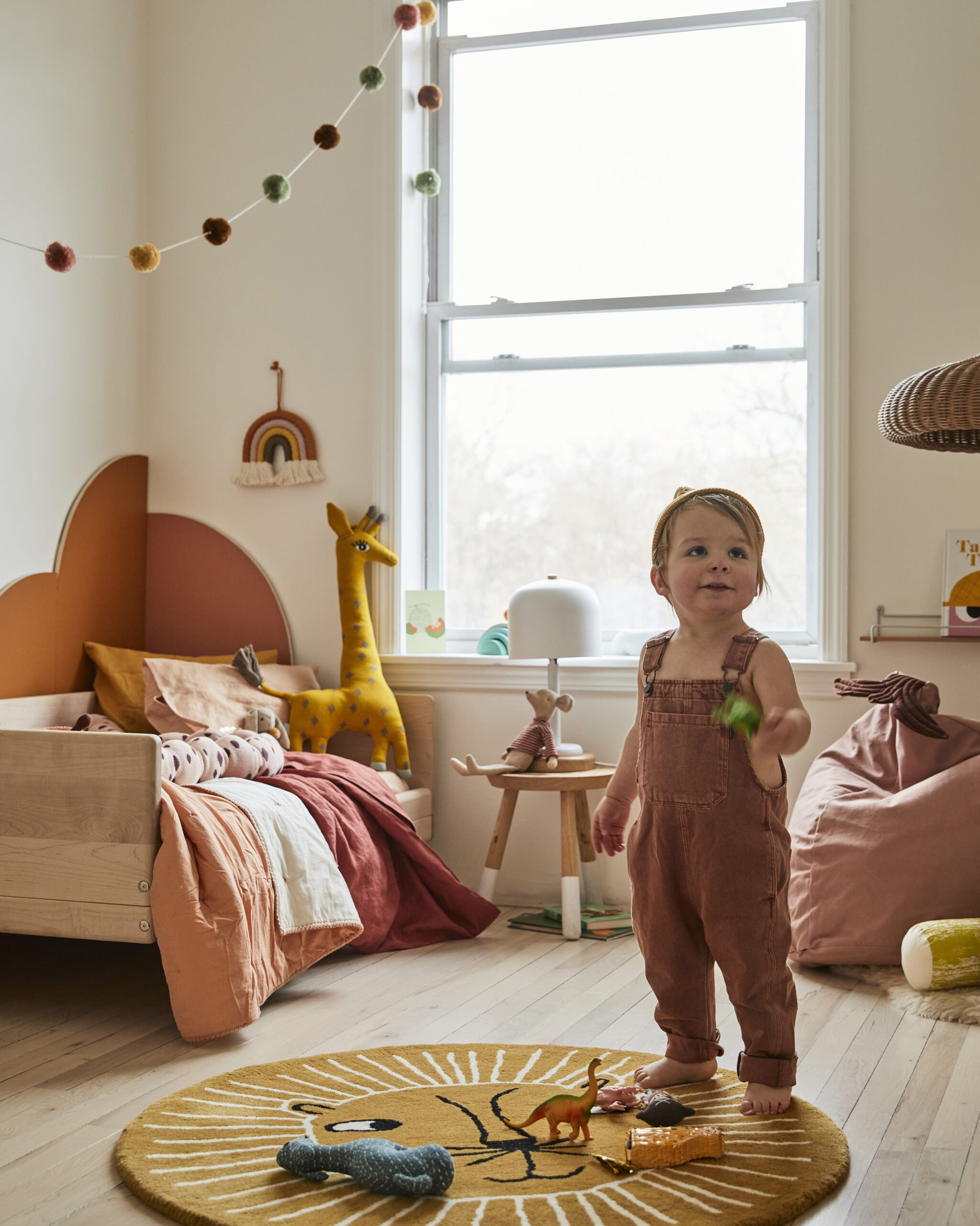 kid’s room with orange arches behind bed and toddler playing