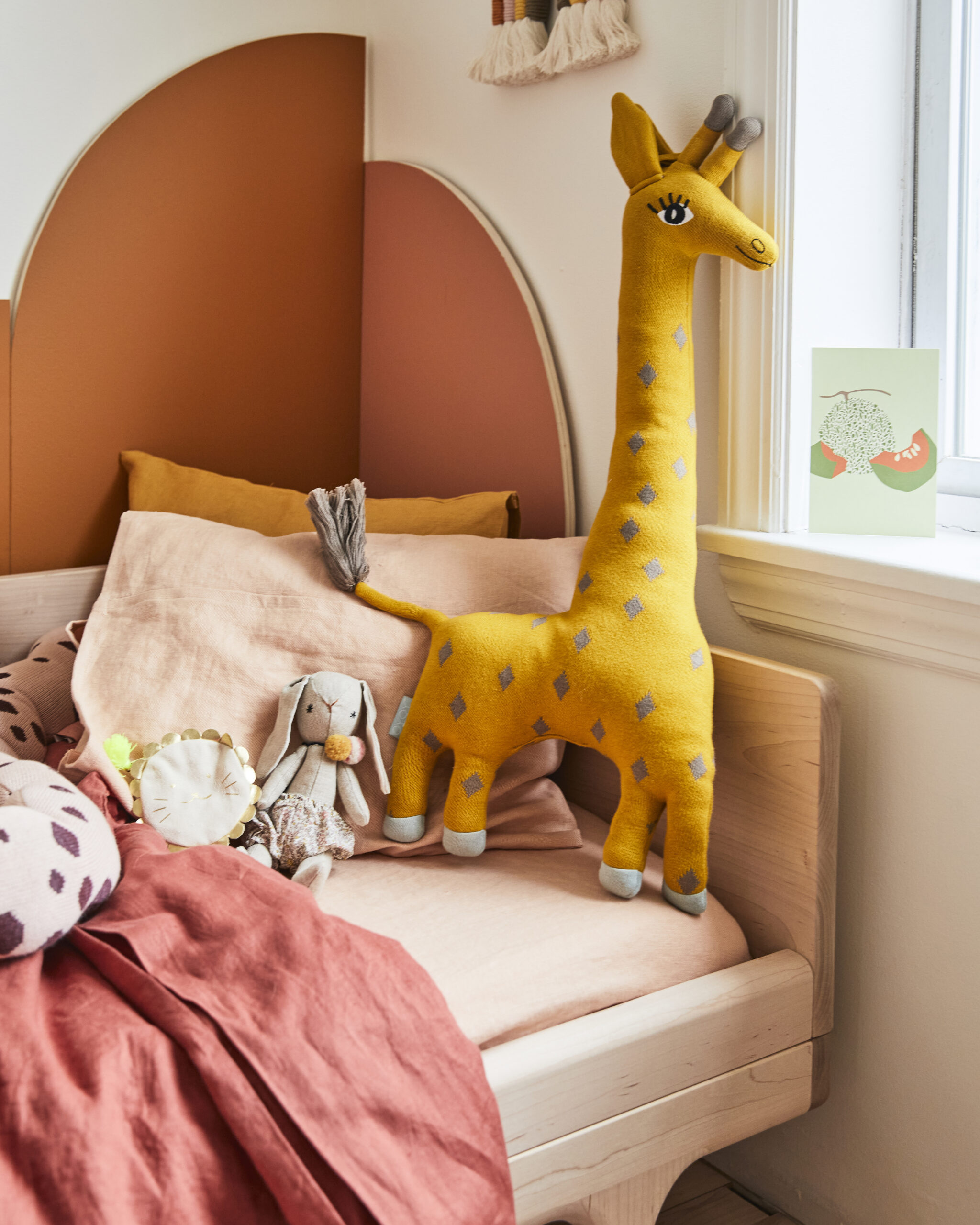 wood kid’s bed with orange arched panels behind it