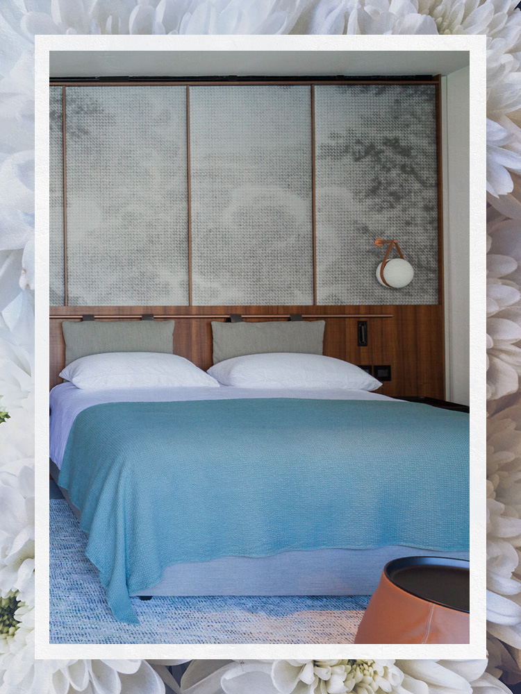 Hotel room with Queen Bed and Pillow Headboard and Wallpaper Walls with Blue Quilt and White Pillowcases