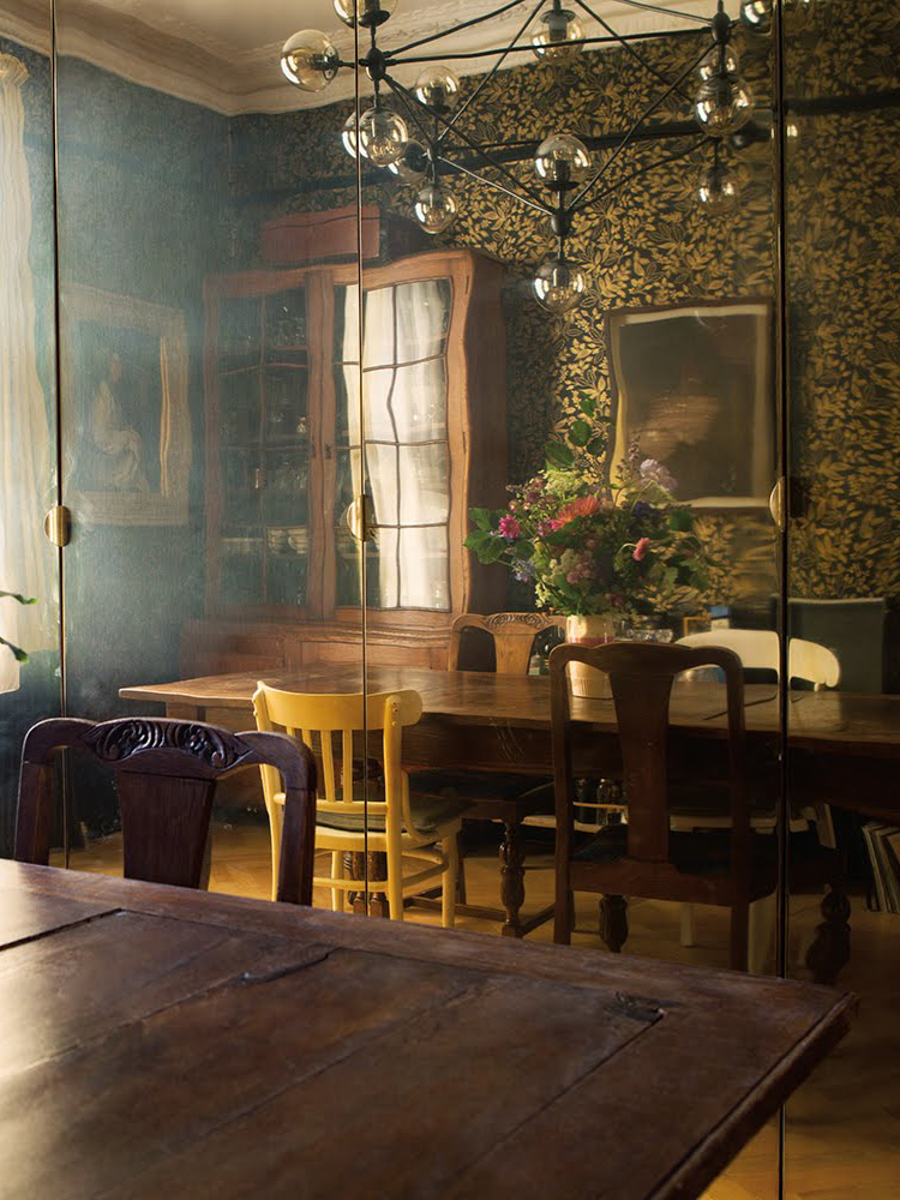 A vintage dining table with vintage mis-matched chairs reflected on a mirror.