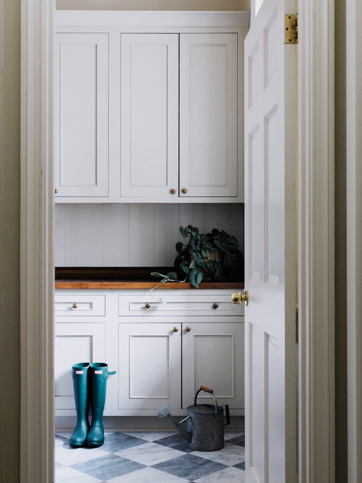 mudroom with white cabinets and marble floors