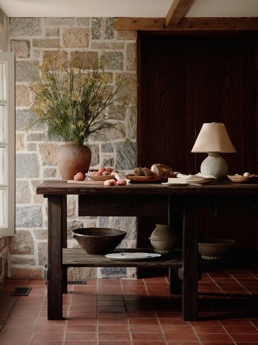 Rustic, dark finished wood island in stone home with lamp and vase