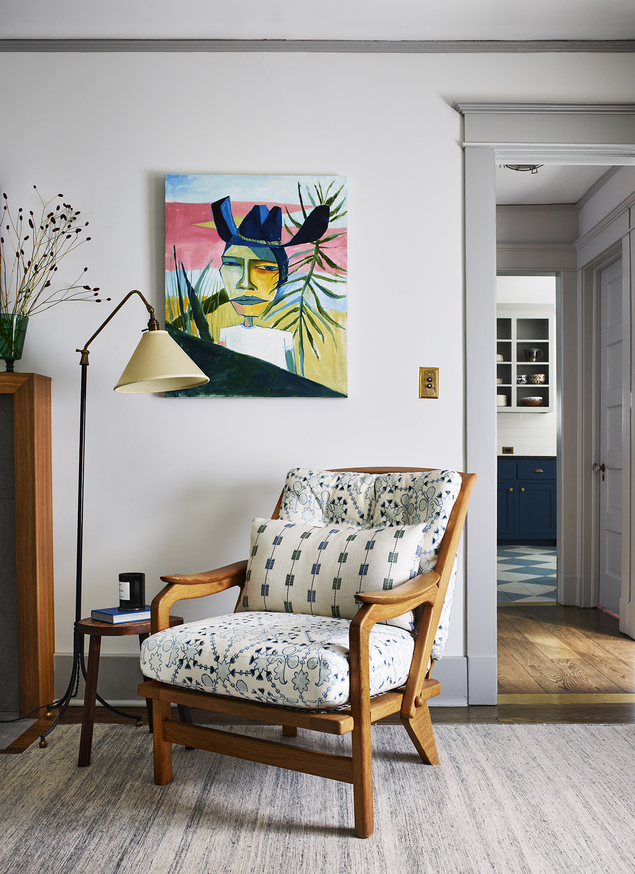 blue and white patterned accent chair below portrait of a cowboy