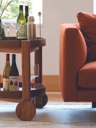 Walnut wood bar cart next to red sofa