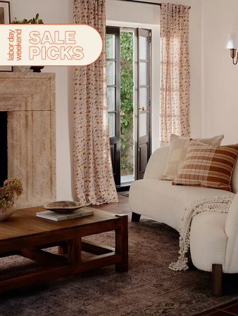 living room with curved sofa and floral printed curtains