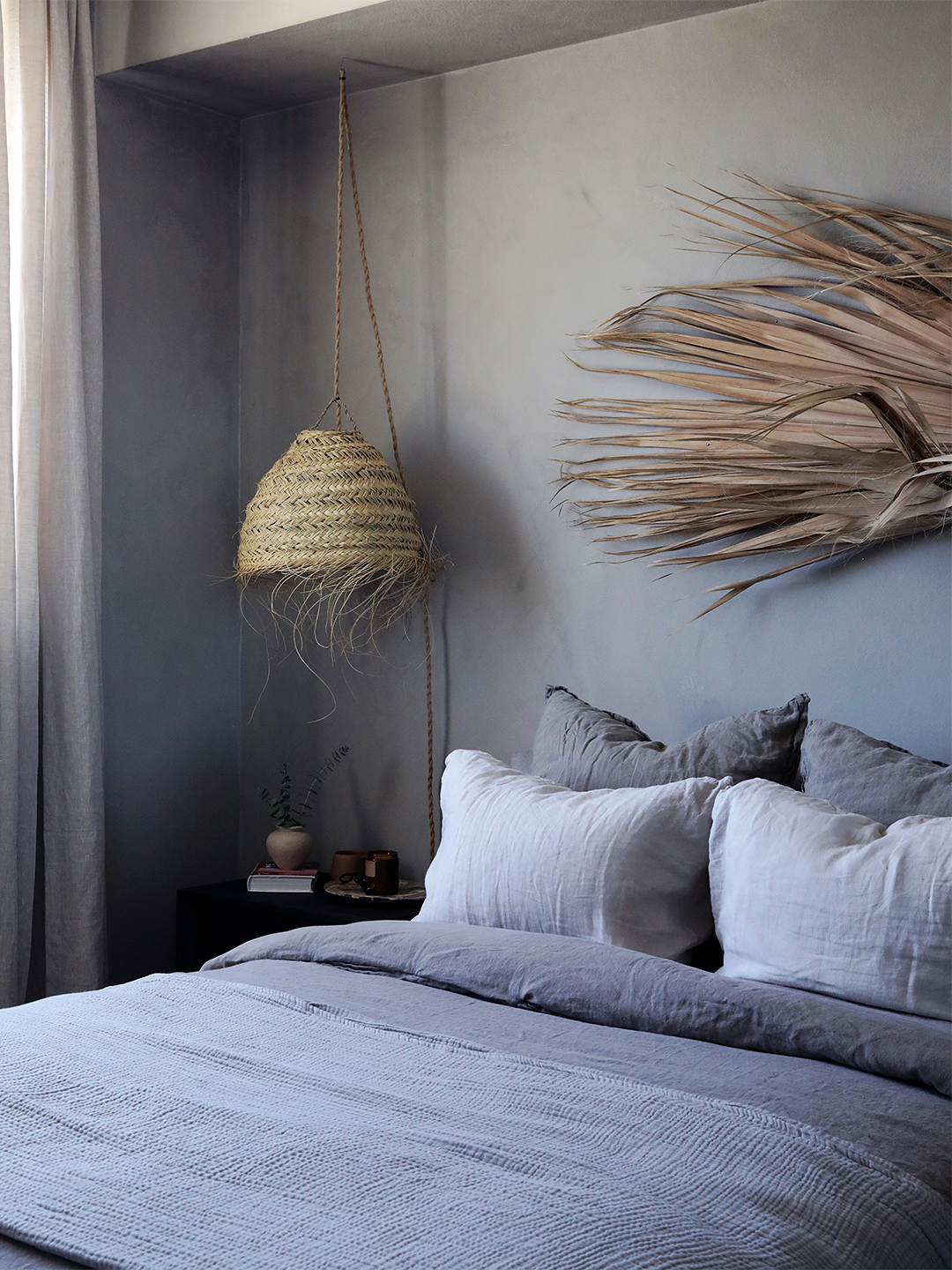 Limewashed bedroom with woven lamp.